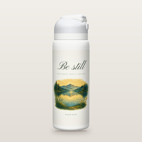 White Owala water bottle with a soft white printed band, the script words Be still above a hand-painted engraving of a still mountain lake at dawn, Psalm 46:10.