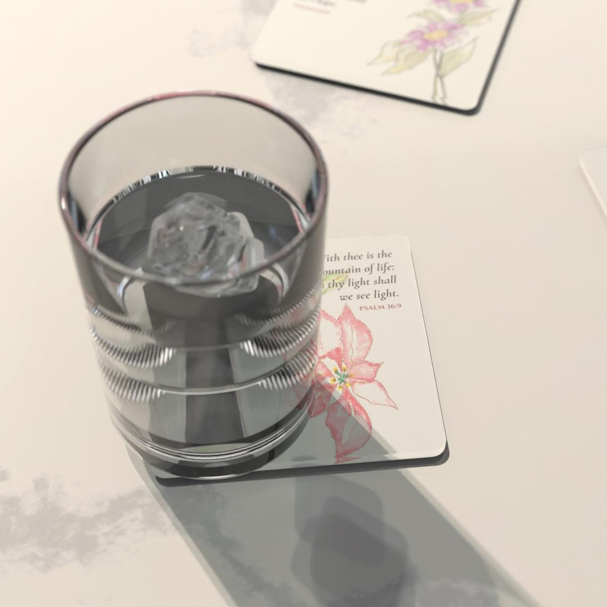 A glass of ice water resting on the Psalm 36:9 coaster, “with thee is the fountain of life”