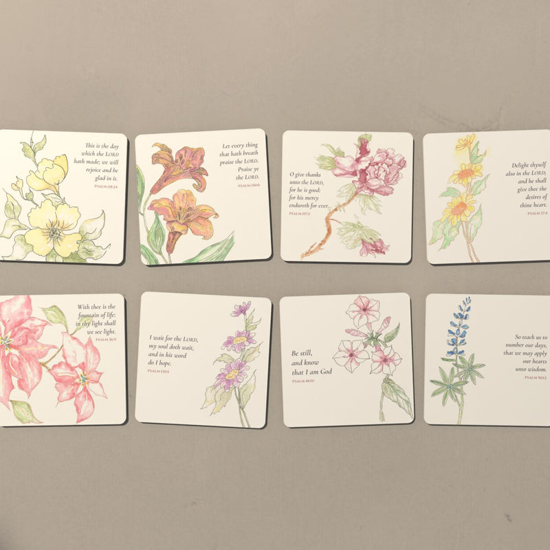 All eight watercolor Psalm coasters laid out in two rows on a warm plaster table